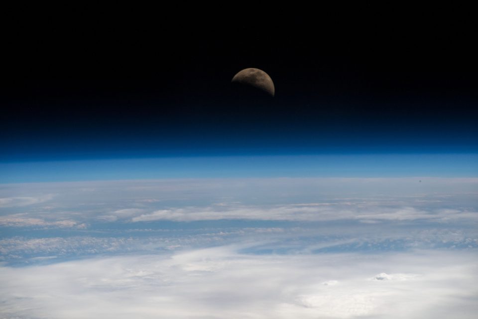 The moon hovers at the edge of the Earth's horizon