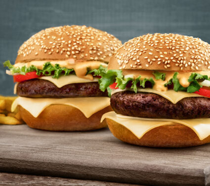 Two,Craft,Beef,Burgers,On,Wooden,Table,On,Blue,Background.