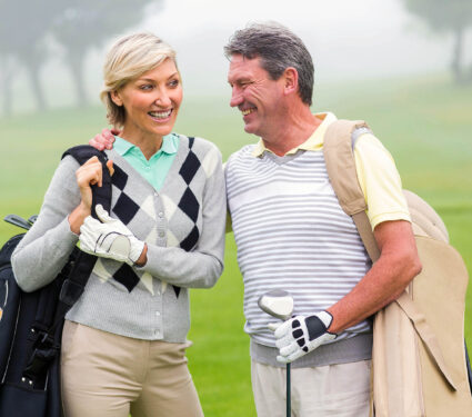 Golfing,Couple,Smiling,And,Holding,Clubs,On,A,Foggy,Day