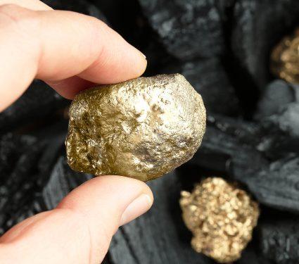 Woman,Holding,Gold,Nugget,On,Blurred,Background,,Closeup.,Space,For